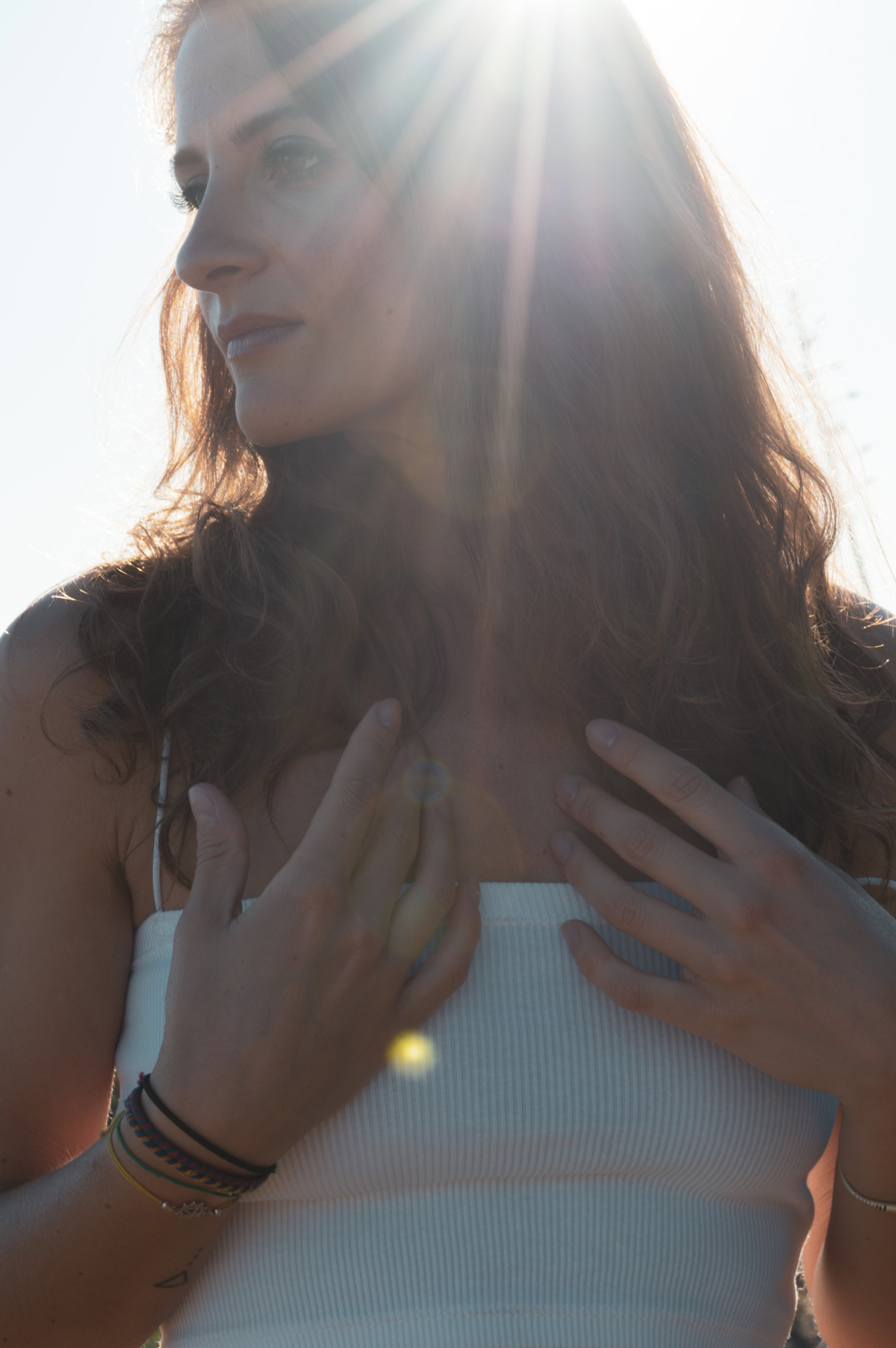 Natalie Montoya, CranioSacral Therapist, with her hands resting on her chest in the sunlight